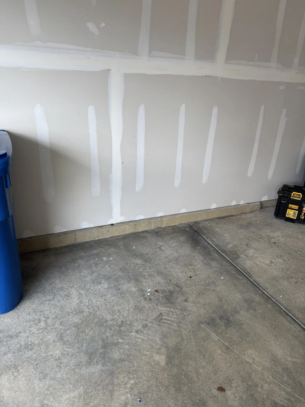 Same garage corner cleared to bare drywall and floor